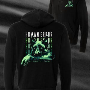May include: Black hoodie featuring a green and white graphic of a German Shepherd dog with the text "HUMAN ERROR" and "THE VERSATILE CANINE." The hoodie also has a smaller graphic on the front and the text "HUMAN ERROR SPRING MMXXIII."