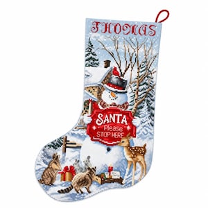 May include: A Christmas stocking featuring a cross-stitch design of a winter scene with a snowman wearing a hat, a deer, a raccoon, and rabbits. The text "THOMAS" is at the top, and a red sign reads "SANTA Please STOP HERE" in white letters.