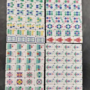May include: A collection of white Mahjong tiles, each with unique symbols and numbers in various colors. The tiles feature designs like dots, flowers, and Chinese characters, arranged in a grid pattern.