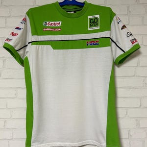 May include: White and green short-sleeved t-shirt with sponsor logos and text. The shirt features a green upper section with "Castrol" and "Barracuda" logos, and the text "GO & FUN". The sleeves have additional logos.