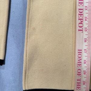 May include: Close-up of a beige knit garment with black trim at the bottom. A Home Depot ruler is placed next to the garment, showing measurements in inches. The text "HOME DEPOT" and "HOME OF THE FINES" are visible on the ruler.