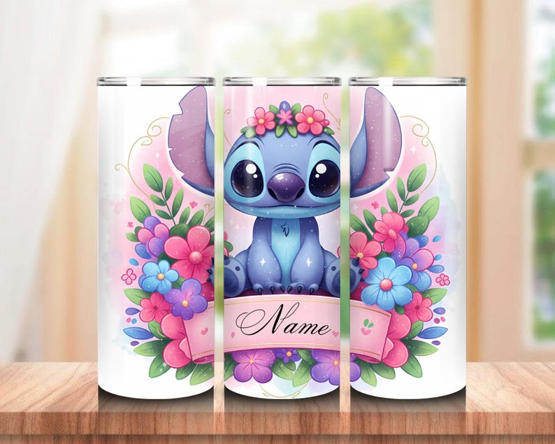 May include: A white tumbler featuring a cartoon character with large eyes, blue fur, and large ears, surrounded by colorful flowers. A pink banner with the word "Name" is across the bottom. The tumbler is on a wooden surface.