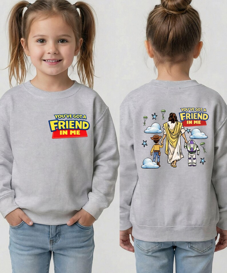 A young girl wearing a gray sweatshirt with a cartoon character and text on the back.