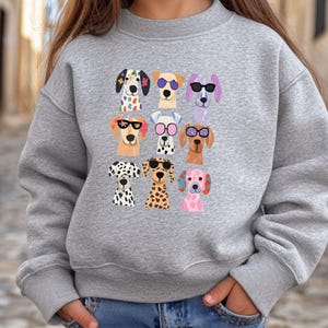 A gray sweatshirt with a graphic of nine cartoon dog faces wearing sunglasses.