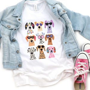 a white t-shirt with a graphic of a group of dogs wearing sunglasses, along with a denim jacket and pink Converse sneakers.