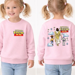 A young girl wearing a pink sweater with a cartoon image of Jesus Christ and the words "You're a friend in me" printed on it.
