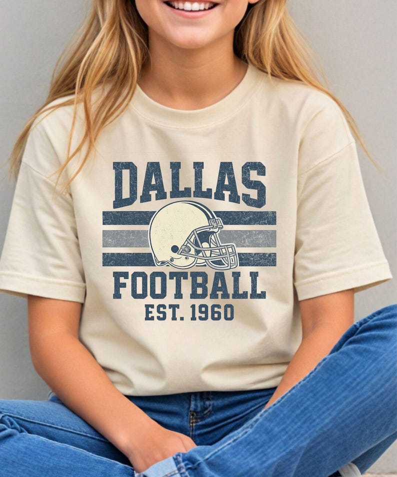 A woman wearing a t-shirt with a graphic design of a football helmet and the text "DALLAS FOOTBALL EST. 1960" printed on it.