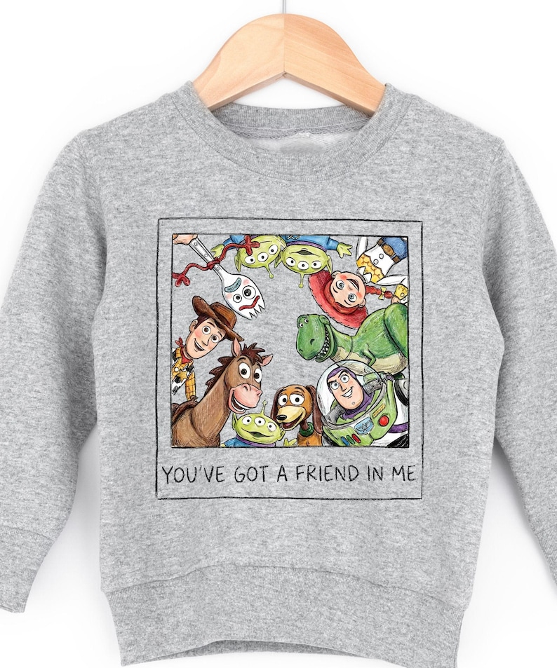 A gray sweatshirt with a graphic design featuring characters from the Toy Story movie, including Woody, Buzz Lightyear, and other beloved characters.
