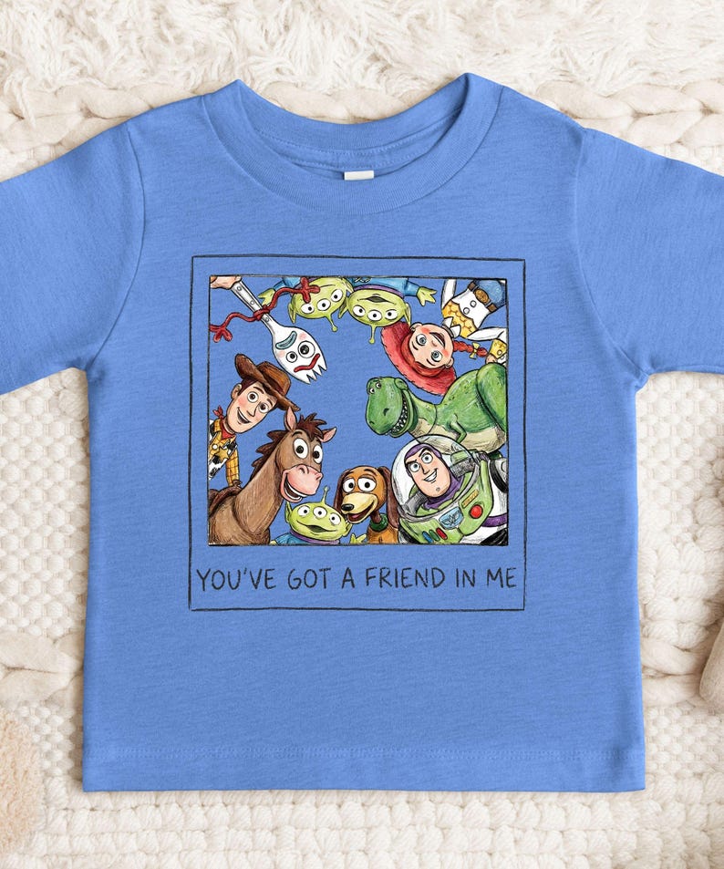 A blue t-shirt with a graphic design featuring characters from the Toy Story movie, including Woody, Buzz Lightyear, and other beloved characters.