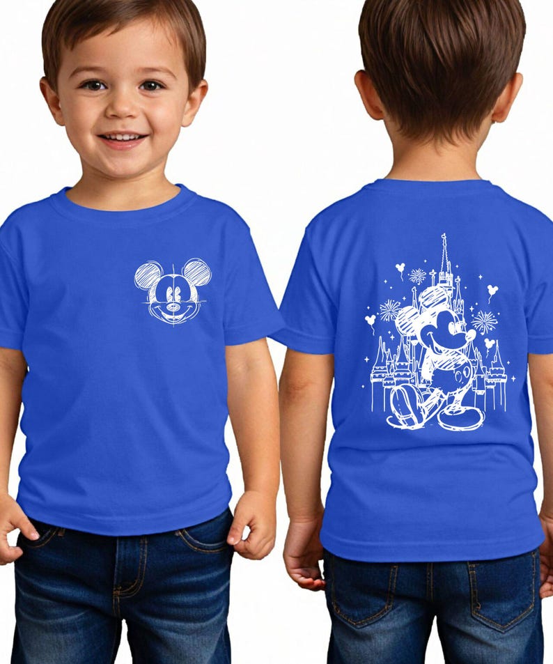 A young boy wearing a blue t-shirt with a Mickey Mouse design on the front and a castle on the back.