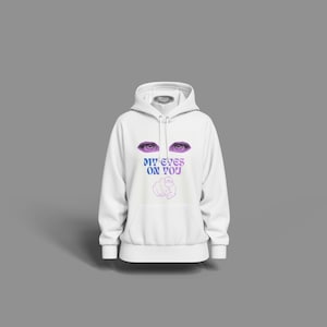May include: A white hoodie with a graphic design on the front. The design features a pair of purple eyes above the text "MY EYES ON YOU" and a fist. The hoodie has a hood and a front pocket.