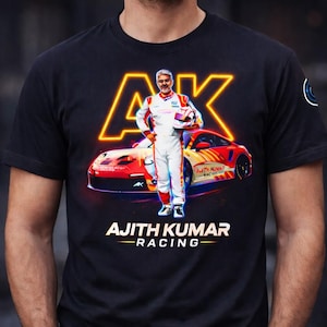 May include: Black t-shirt with a racing theme. The design shows a race car and a driver in a white racing suit. The text "AJITH KUMAR - RACING" is displayed in white, with a neon yellow "AK" logo above.