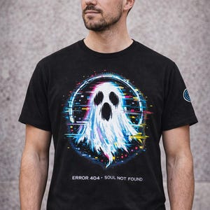 May include: Black t-shirt with a digital art ghost design inside a glitching circle. The ghost is white and blue with colourful accents. Text at the bottom reads "ERROR 404 • SOUL NOT FOUND". A small logo is on the right sleeve.