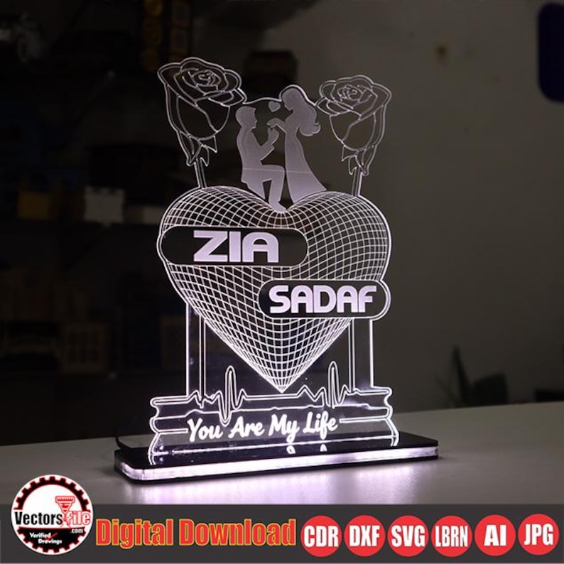 May include: A lighted heart-shaped decorative piece with the names "ZIA" and "SADAF" on it. The design includes a couple, roses, and the text "You Are My Life". The base is black, and the piece is illuminated.