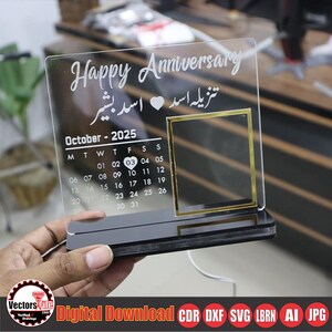 May include: Clear acrylic anniversary calendar with a black base. The calendar features the words "Happy Anniversary" and a calendar for October 2025. A gold-framed area is on the right side. The text "Digital Download" is at the bottom.
