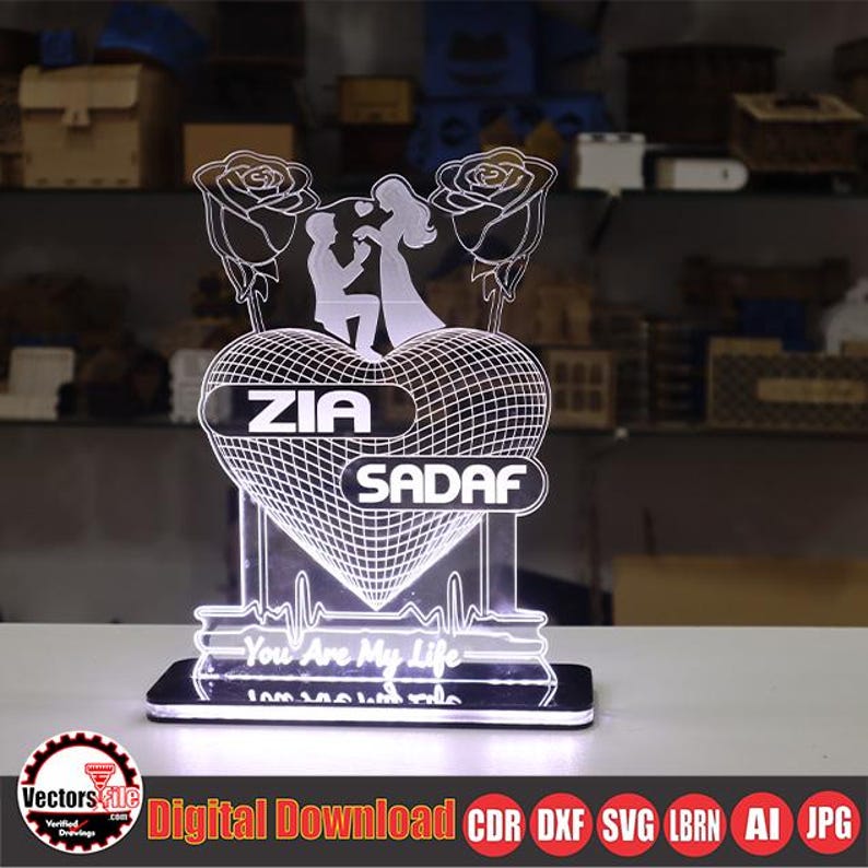 May include: A glowing LED night light featuring a heart-shaped design with the names "ZIA" and "SADAF". The light includes a silhouette of a couple and two roses. The base has the text "You Are My Life".