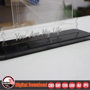 May include: A clear acrylic LED night light with the phrase "You Are My Life" etched on the front. The base is black and rectangular. The design includes a heartbeat line and a geometric shape.