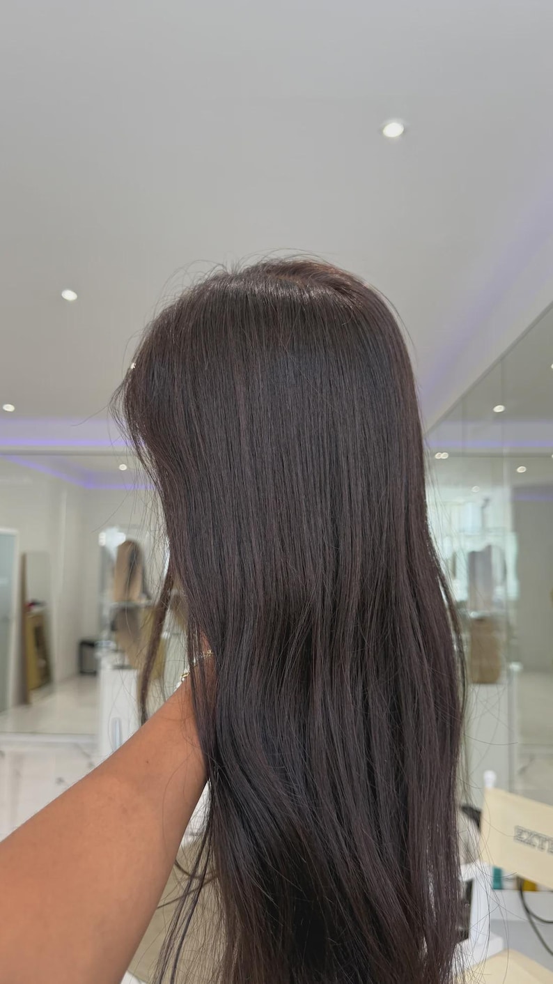 May include: A long, straight hair extension piece in a dark brown shade. The hair is smooth and sleek, featuring a natural-looking texture that flows downward. The strands are uniform in color, providing a consistent appearance from the top to the ends.