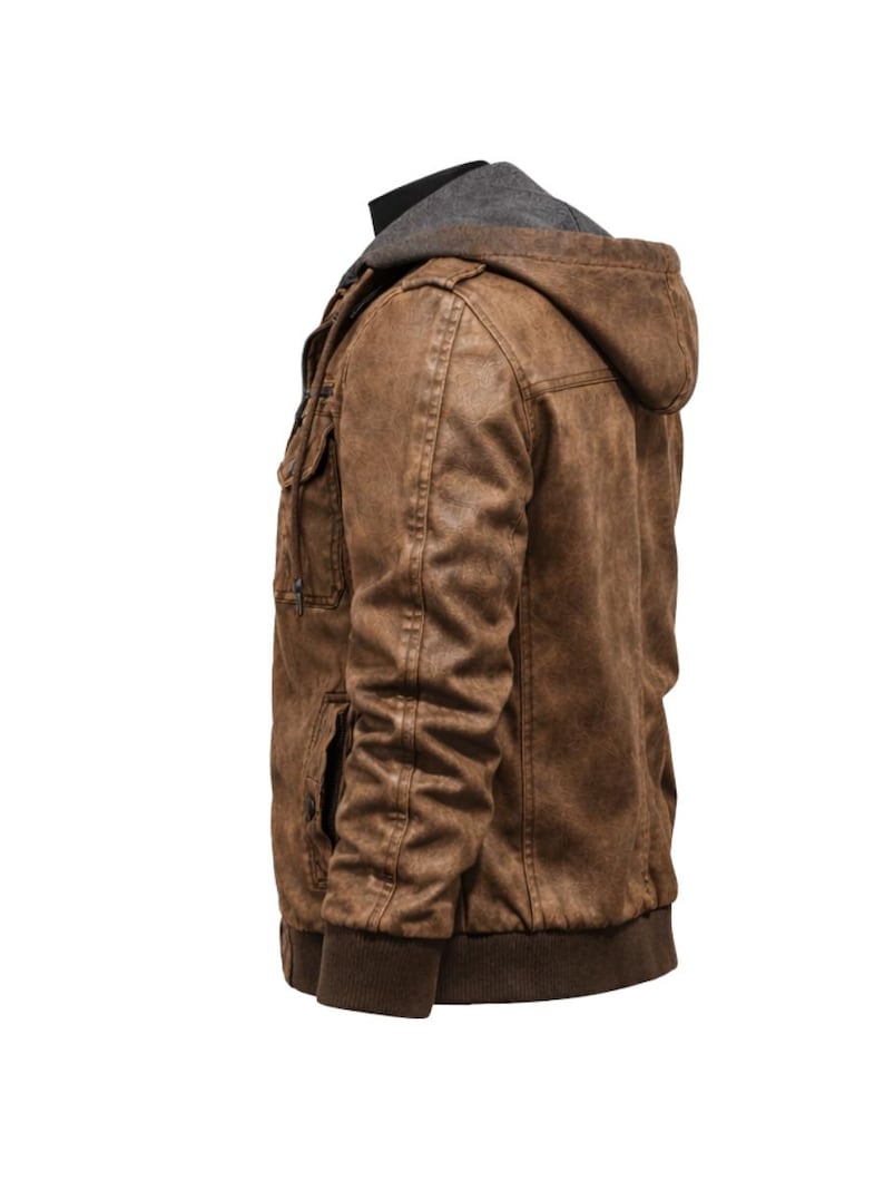 May include: Brown faux leather jacket with a grey hooded lining. The jacket features multiple pockets, a ribbed hem, and cuffs. The jacket is designed with a vintage, distressed look.