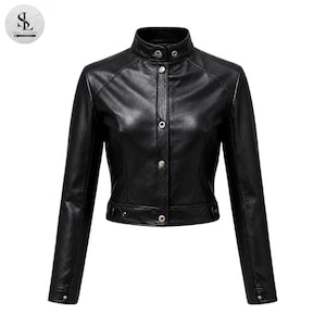 May include: A black leather jacket featuring a high mandarin collar, long sleeves, and a front placket with silver-toned snap button closures. The jacket has a cropped length, structured shoulders, and a smooth finish with visible seam detailing.