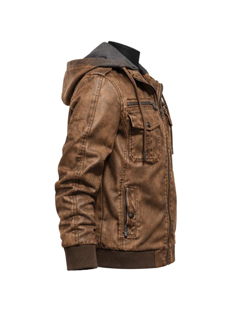 May include: Brown faux leather jacket with a grey hooded insert. The jacket features multiple pockets, a zip closure, and ribbed cuffs and hem. The jacket is designed with a distressed finish.