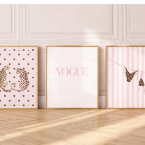 May include: Three framed art prints with gold frames. The left print features two leopard figures on a pink polka dot background. The centre print displays the word "VOGUE" in pink. The right print shows a leopard print bikini.