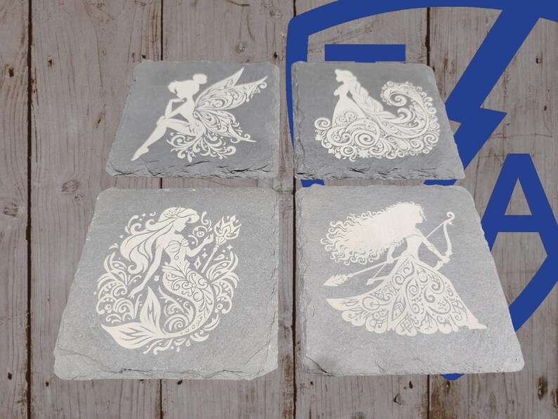 May include: Four gray slate coasters with white etched designs. Each coaster features a different fairytale character: a fairy, a princess, a mermaid, and a warrior princess. The coasters are square with irregular edges.