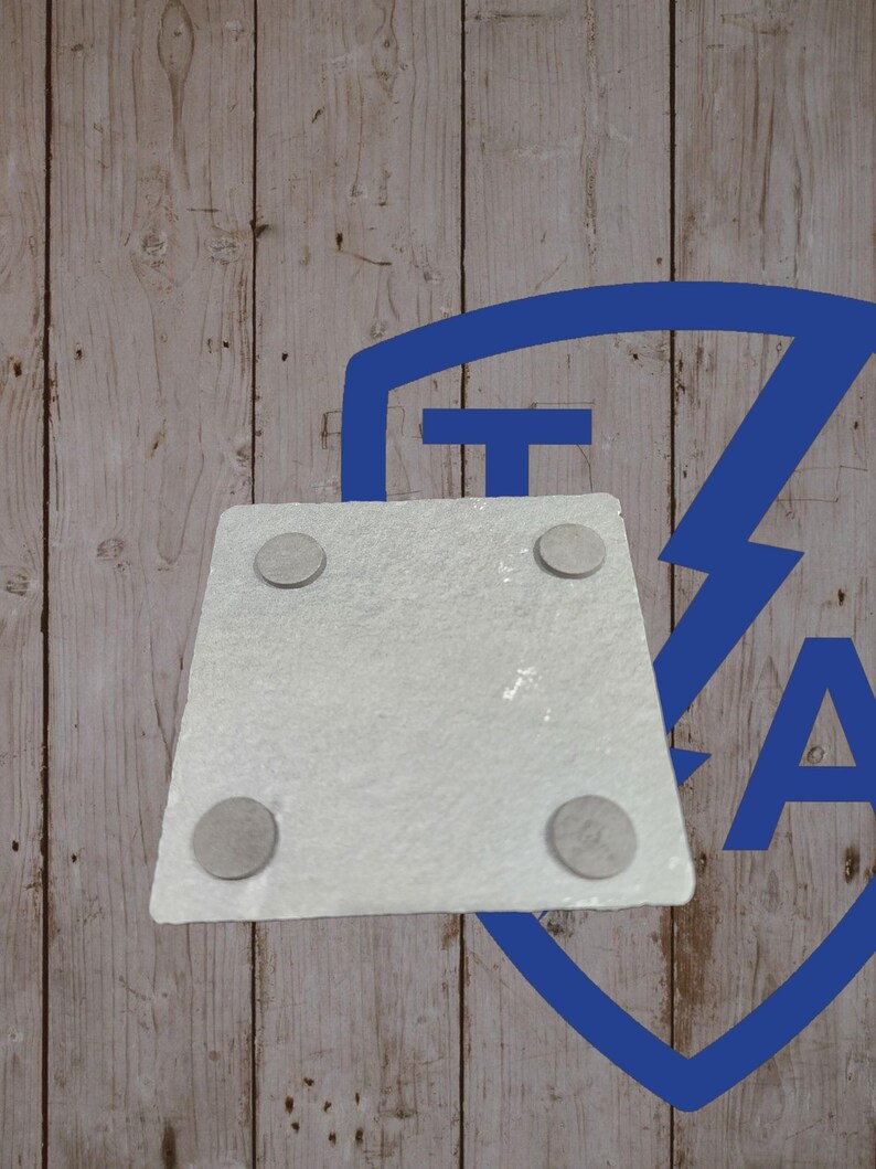 May include: A square, light gray stone coaster with four small, round, gray pads on the underside. The coaster is set against a light brown wooden background with a blue graphic in the upper right corner.