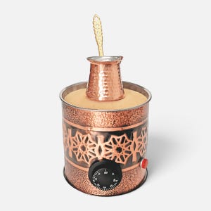 May include: A copper-colored electric coffee sand heater with a textured finish and a geometric cutout pattern. It features a black temperature control dial, a small red power indicator light, and a copper coffee pot resting on the sand surface.