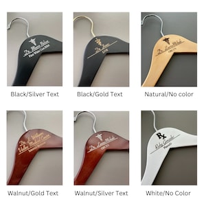 May include: Six wooden hangers with different finishes and text engravings. The hangers are black, natural wood, walnut, and white. The text engravings include names, titles, and medical specialties.