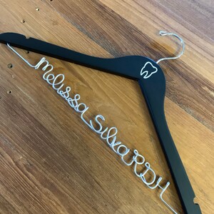 May include: Black wooden hanger with a silver wire name "Melissa Ward" and a tooth graphic.