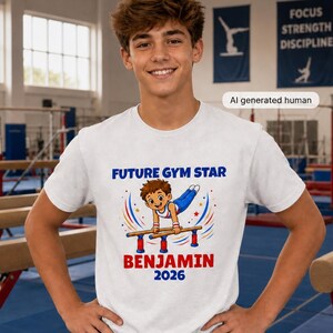 May include: A white short-sleeved t-shirt featuring a graphic of a cartoon gymnast on parallel bars with the text FUTURE GYM STAR, BENJAMIN, and 2026. The design includes blue and red accents, and the shirt is paired with blue athletic shorts.