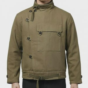 Pode incluir: Casaco verde-oliva com gola alta, fechos de botões e um bolso frontal. O casaco apresenta um cinto na cintura e detalhes de botões nas mangas. O casaco é feito de um tecido durável e tem um design clássico e utilitário.