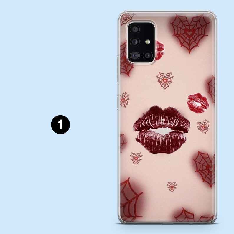 Puede incluir: Una funda de tel&eacute;fono con un fondo rosa que presenta una gran huella de labios rojo oscuro y huellas de labios rojas m&aacute;s peque&ntilde;as. La funda tambi&eacute;n tiene dise&ntilde;os de telara&ntilde;as y corazones rojos.