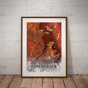 May include: Framed map print of Copenhagen, Denmark, with a detailed city layout in shades of orange and brown. The word "KOPENHAGEN" is printed in white at the bottom. The print is in a brown frame, set against a white background and wooden floor.