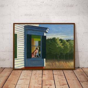 May include: A framed print of a painting depicting a woman looking out a window. The painting features a white house with green shutters, a blue sky, and a field of tall grass. The woman is wearing a red dress.