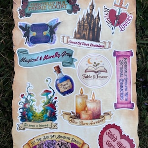 Puede incluir: Una colección de pegatinas de temática fantástica sobre una hoja estilo pergamino. Los diseños incluyen un castillo, una espada atravesando un corazón, una poción etiquetada como Faerie Tears, velas, setas y pancartas con textos variados.