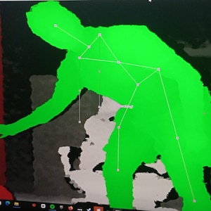 May include: A computer screen shows a green silhouette of a person with connected lines and nodes, possibly for motion tracking. The background has red, grey, and green blocks, with the word "Tracking!" visible.