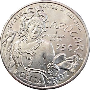 May include: A silver-colored United States quarter coin featuring a relief portrait of Celia Cruz. The coin includes the text "UNITED STATES OF AMERICA", "¡AZÚCAR!", "E PLURIBUS UNUM", "25¢", and "CELIA CRUZ". The design shows a smiling figure holding a microphone.