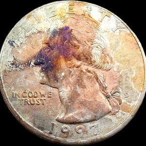 May include: A 1997 United States quarter dollar coin featuring a profile portrait of George Washington. The coin displays significant surface discoloration with patches of copper-toned oxidation, dark purple staining, and the text LIBERTY, IN GOD WE TRUST, and the date 1997.
