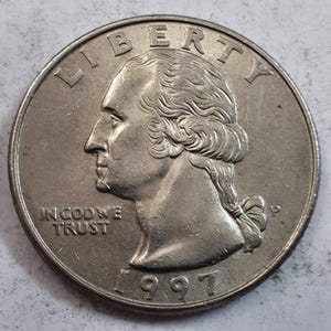 May include: A silver-colored 1997 United States quarter dollar coin featuring the profile of George Washington facing left. The text LIBERTY is arched at the top, IN GOD WE TRUST is on the left, and the letter P mint mark is on the right.