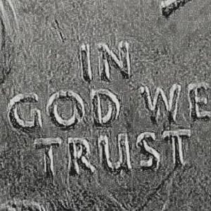 May include: A close-up view of a metallic surface featuring the embossed text IN GOD WE TRUST. The lettering is raised and appears in a silver-toned finish with a textured, weathered background that shows signs of wear and small surface scratches.