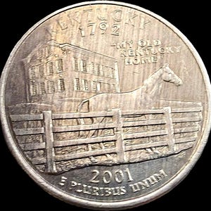 May include: A silver-colored Kentucky state quarter coin featuring a relief of a horse standing behind a wooden fence in front of a large building. The text reads KENTUCKY 1792, MY OLD KENTUCKY HOME, 2001, and E PLURIBUS UNUM on the coin surface.