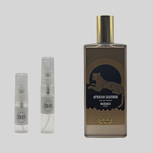May include: A perfume bottle and two sample vials. The rectangular perfume bottle is brown with a gold cap and features the text "AFRICAN LEATHER" and a leopard illustration. The vials have the letters "BiB" on them.