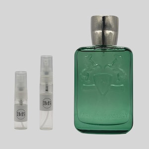 May include: A green rectangular perfume bottle with a silver cap, embossed with a crest and the text "PARFUMS de MARLY PARIS". Two small clear spray bottles with "BiB" labels are next to the perfume bottle.