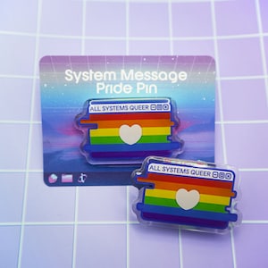 May include: Two rainbow pride pins with a white heart in the center. The pins are shaped like a computer window with the text "ALL SYSTEMS QUEER" at the top.