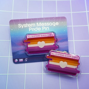 Op de afbeelding: Twee transparante acryl-pins met een ontwerp van een lesbische pride-vlag. De pins zijn gevormd als een computervenster met de tekst "ALL SYSTEMS QUEER" bovenaan. De tekst is in wit lettertype op een zwarte achtergrond. De vlag is in de kleuren oranje, wit, roze en een wit hart in het midden.