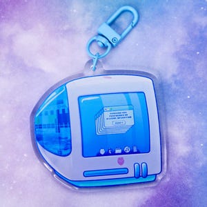May include: A blue and white computer-shaped keychain with a blue clasp. The screen displays a stack of windows with text. The keychain has a retro aesthetic and a heart-shaped design at the bottom.