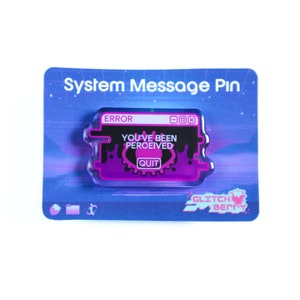 May include: A System Message Pin on a blue card with a starry background. The pin is shaped like a computer error message, with the words "ERROR", "YOU'VE BEEN PERCEIVED", and "QUIT". The pin has a purple and black color scheme.