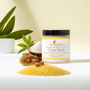 May include: A white jar with a black lid labeled "bee naturals" and "Clean Nails" with the text "The Safer Alternative Nail Polish Remover" and "net weight 4 oz (113.40 grams)".